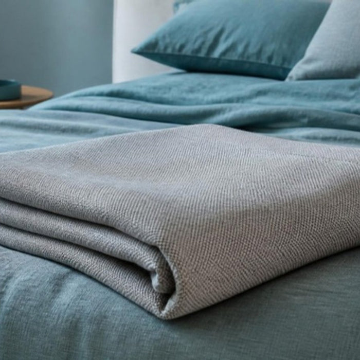 EMF blanket with silver Faraday shielding fabric folded on a bed