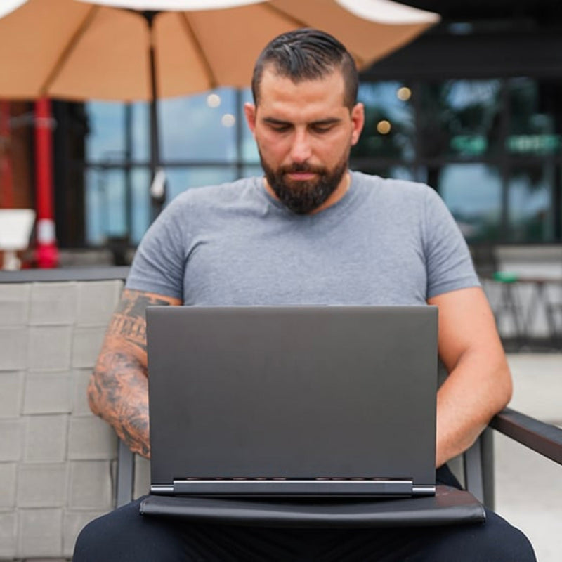 Man using DefenderShield® Cybersecurity RFID EMF Protection Laptop Sleeve on a sofa outside in the UK